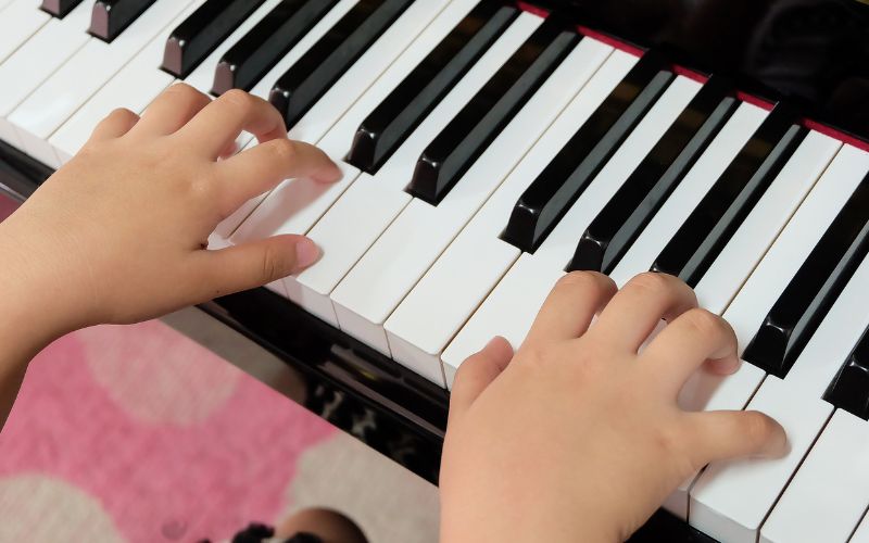 Lapsen kädet pianon koskettimilla.