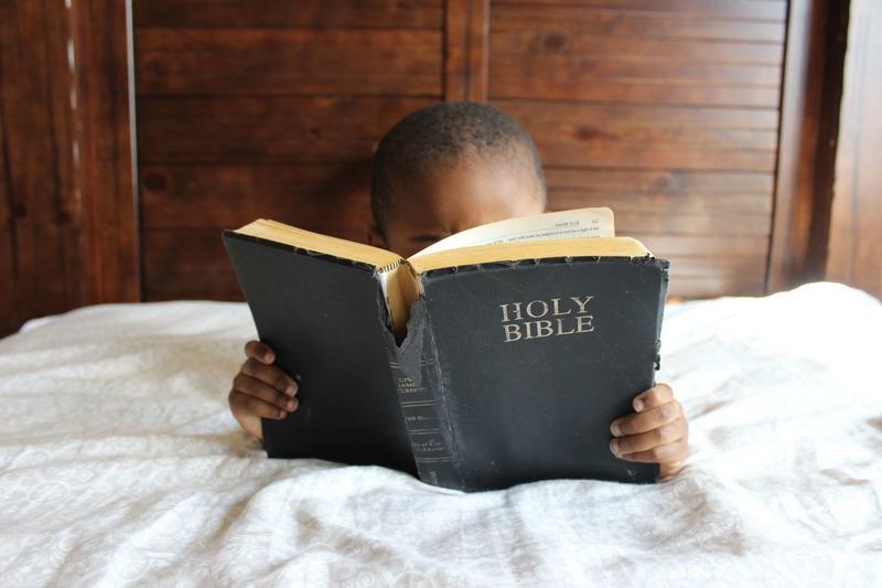 Lapsi lepää ja lukee  raamattua.