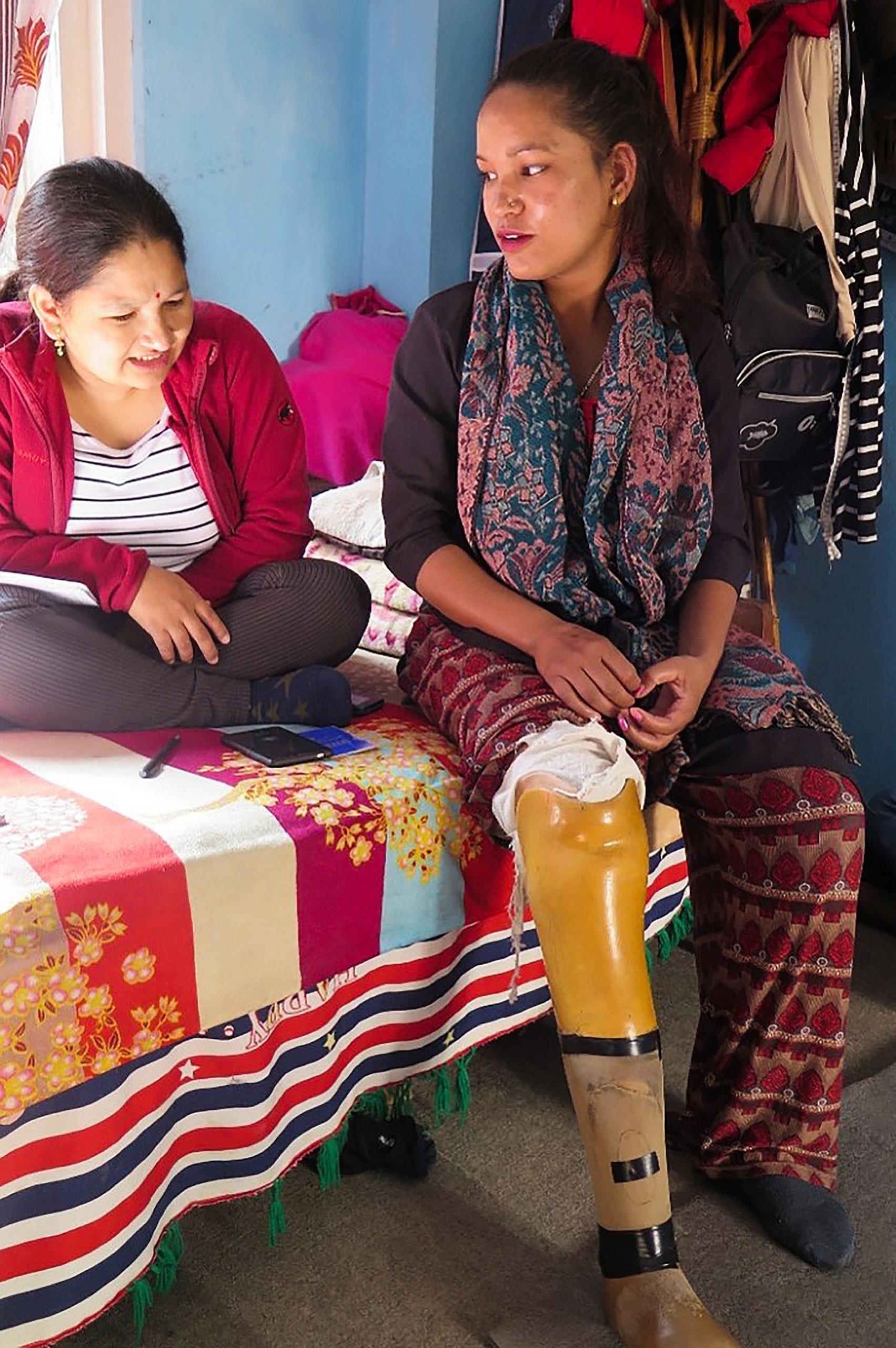 Nepalilainen tyttö, jolla on jalassa proteesi. Toinen tyttö istuu hänen vieressään.