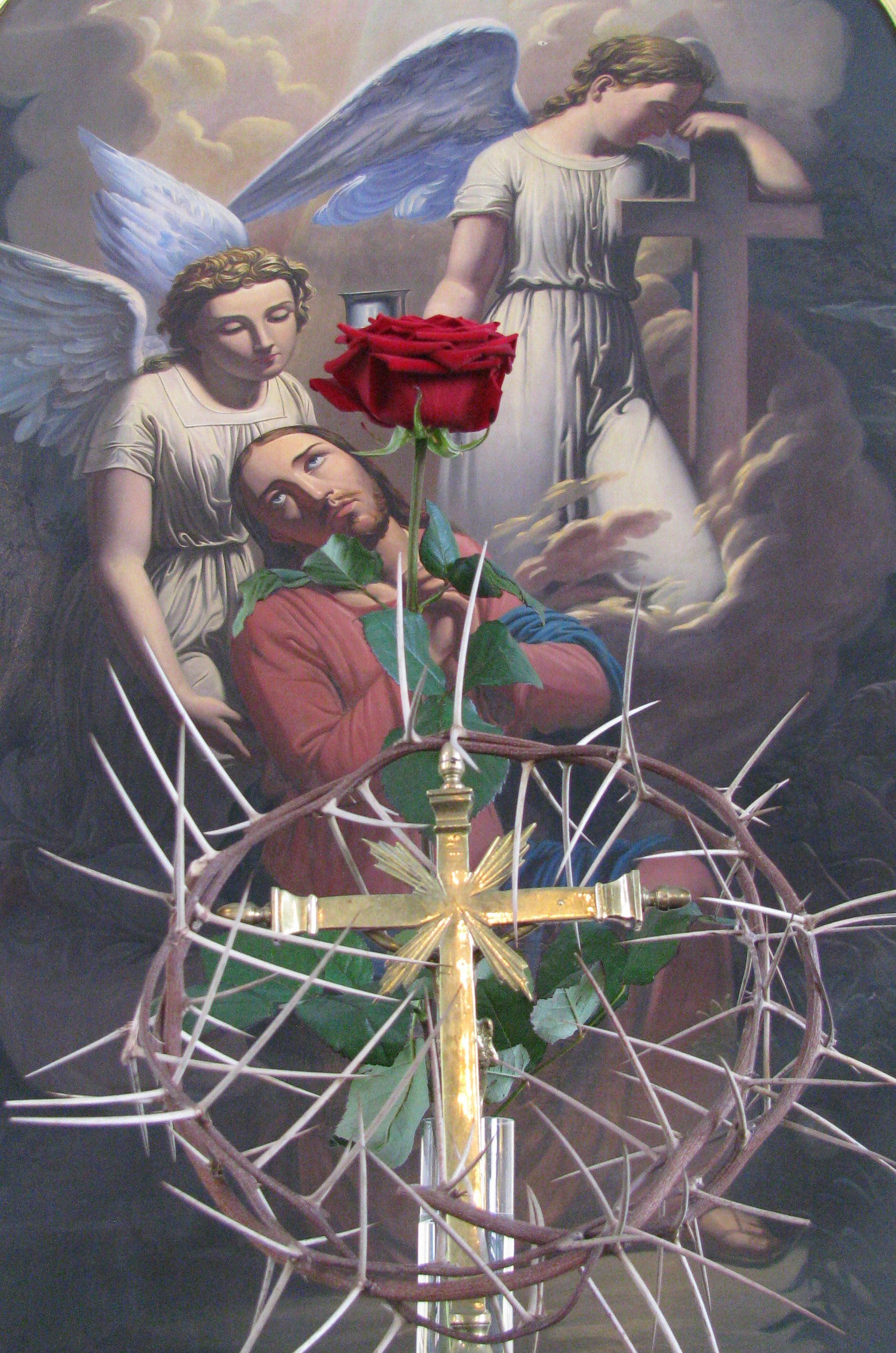 Hämeenkyrön kirkon alttaritaulu, jossa Jeesus ja kaksi enkeliä. Edessä risti, ruusu ja piikkikruunu.