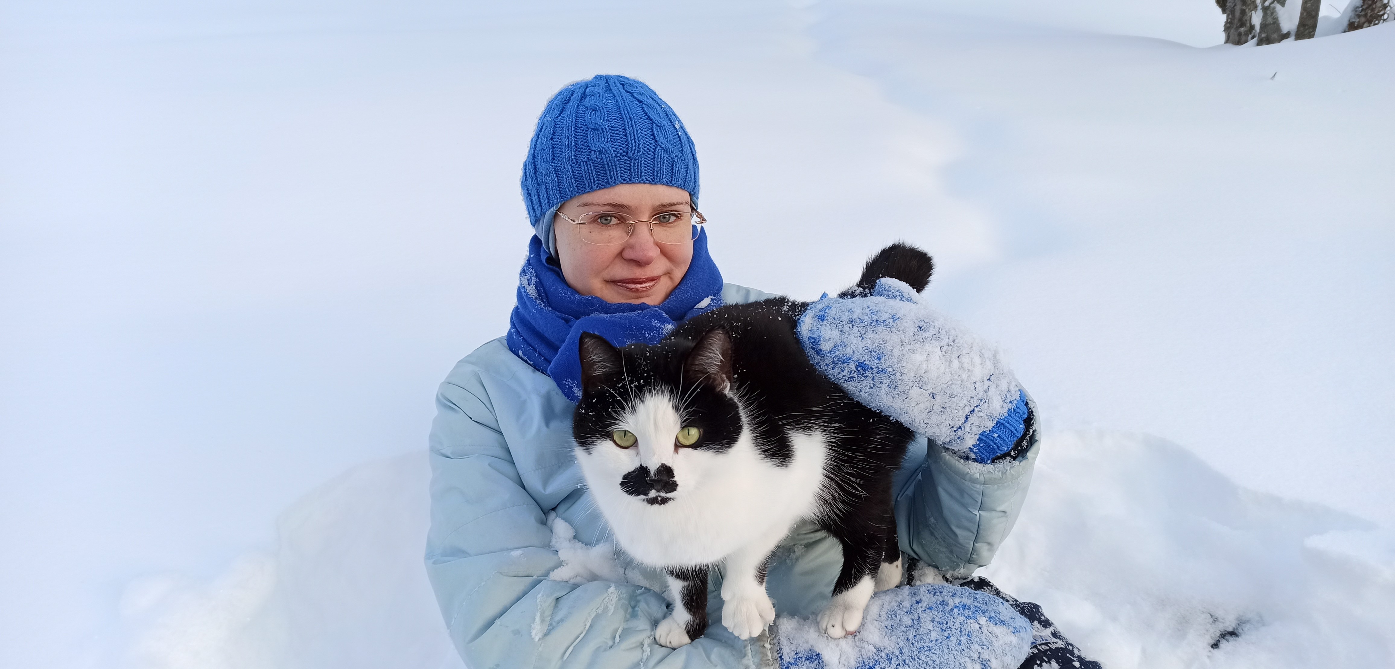 Kuvassa Anu-pappi Lumikki-kissan kanssa lumessa