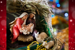 Maria, Joosef ja Jeesus -lapsi tallissa. Ympärillä joulukoristeita.