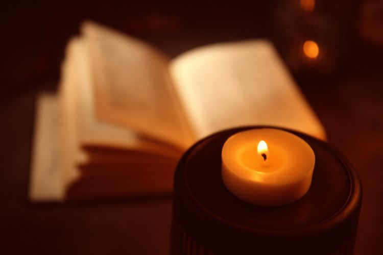 Palava kynttilä ja taustalla avoin Raamattu.