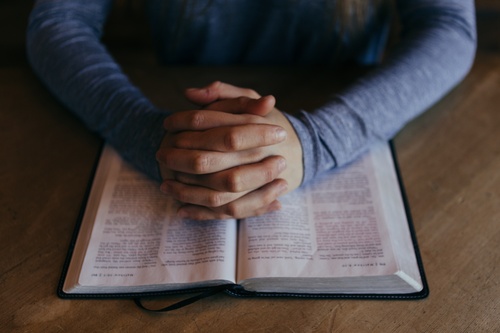 Raamattu ja rukoilevat kädet.